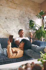 Poster - Couple, book and phone with relax in home for bonding together, reading hobby and streaming service. African people, relationship and weekend break with fantasy novel, online video and social media