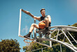 © peopleimages.com - Basketball, sports and man on net at court in outdoor park for match, competition and game. Blue sky, thinking and person on hoop for goal, score and practice in training, fitness and exercise