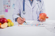 © R Photography - A male nutritionist works at his desk, discussing the benefits of eating fruit. He analyzes diets and educates patients on healthy eating habits for optimal health and well-being