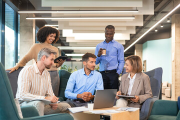 Wall Mural - Group of young modern people in formalwear using modern technologies while working in the creative office