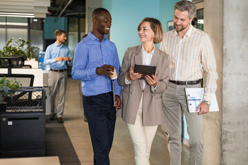 Wall Mural - Three business people discussing work together using a tablet in a modern office