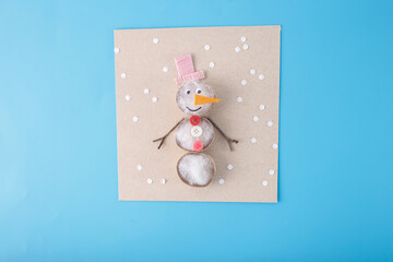 Wall Mural - Handmade snowman craft made of natural materials on beige cardboard. Flat lay with copy space. Winter holidays and Christmas celebration. Design for greeting card, invitation, postcard