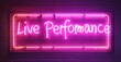 © antishock - Live Performance neon sign glowing in pink, framed by illuminated tubing, mounted on a textured brick wall, creating a vibrant stage-inspired ambiance with a retro feel