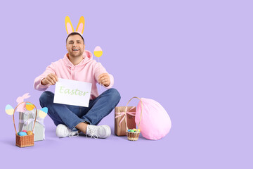 Canvas Print - Happy young man in bunny ears celebrating Easter on purple background