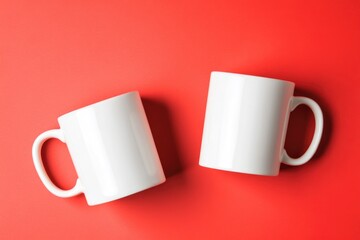 Wall Mural - Two white coffee mugs placed on a bright red surface