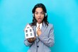 © luismolinero - Real estate hispanic agent holding a toy house isolated on blue background with surprise facial expression