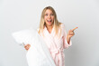 © luismolinero - Young blonde woman isolated on white background in pajamas and surprised while pointing finger to the side