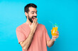© luismolinero - Young man over holding a cocktail over isolated blue background