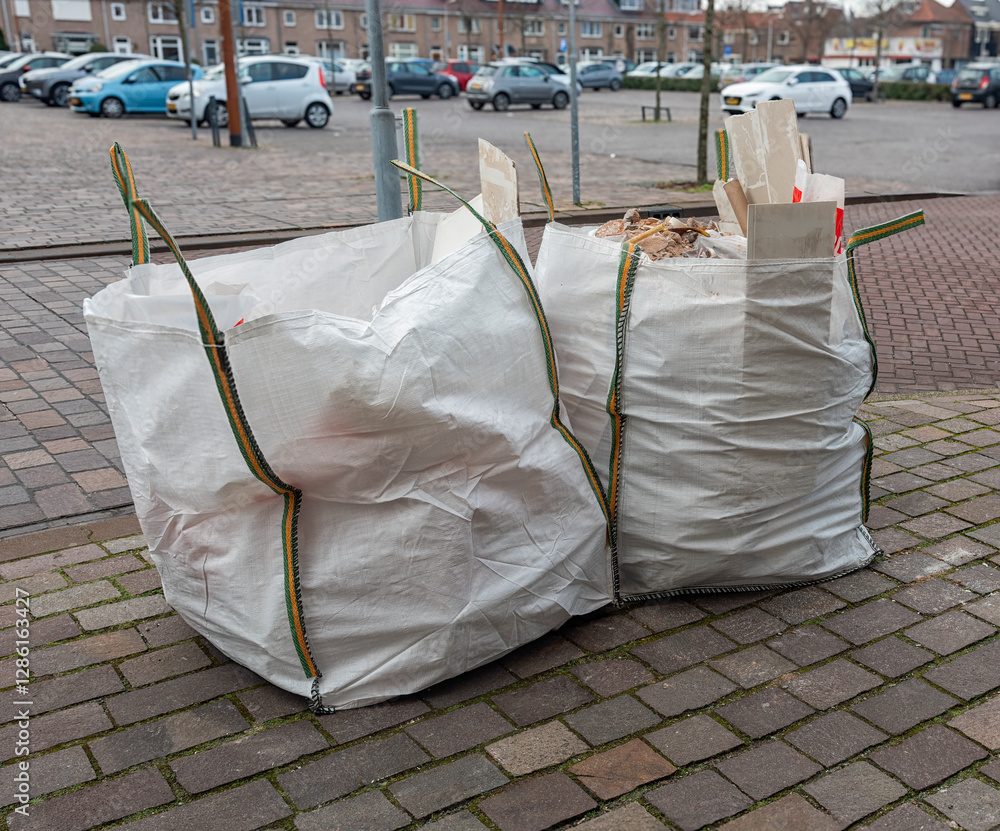 two large white jute construction waste bags filled with waste