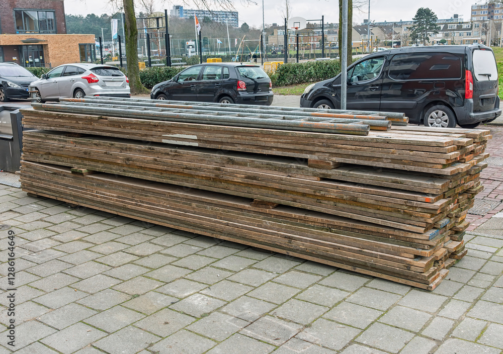 wooden scaffolding planks are stacked on top of each other outside on the sidewalk