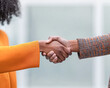 © Kowit - Two individuals shaking hands, symbolizing agreement and collaboration, with one wearing an orange garment and the other in a patterned outfit.