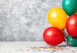 © A4719 - Colorful balloons and confetti on a gray background. A festive image perfect for celebrations and parties