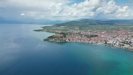 Wall Mural - Drone view of tranquil blue water of Lake Ohrid with overpopulated town and hilly background