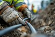 © VITALII - Cable Installation. Worker's hands installing underground cable, selective focus.