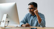 © Postmodern Studio - A man wearing glasses is sitting at a desk in front of a computer monitor