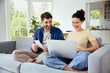 © baranq - Carefree couple calculating home finances sitting together with laptop on sofa