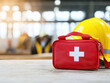 © AbsoluteAi - Construction site worker safety and first aid kit. A red first aid kit and yellow hard hat on a work surface, symbolizing workplace safety and health preparedness.