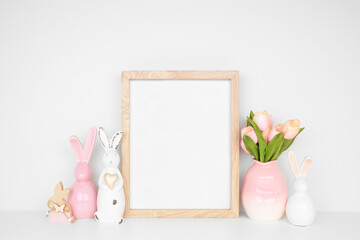 Wall Mural - Modern Easter home decor shelf scene. Mock up portrait wood frame with Easter bunnies and tulip flowers on a white shelf. Copy space.