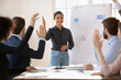 © fizkes - Group of young teammates voting unanimously at meeting in conference room, raise hands, celebrate shared success at office briefing, involved in teambuilding activity, teamwork. Initiative, solidary