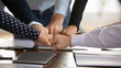 © fizkes - Team fists bumping gathered together at conference table, gesture of successful teamwork, unity, effective collaboration and synergy. Collective agreement, shared commitment to achieving common goals