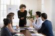 © fizkes - African woman leading discussion or presentation during business meeting in conference room, engaging in dialogue with colleague, exchanging ideas, solutions, gathered together for decision making