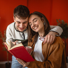 young couple drink coffee and read book together in modern living room