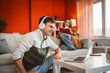 © Miljan Živković - man work from home on laptop while woman read a book on sofa