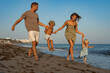 © sutulastock - Family Running and Holding Hands on the Beach by the Ocean at Sunset