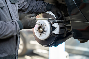 Poster - Serviceman checks the brake discs of a car