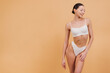 © anatoliycherkas - Beautiful Asian Woman Posing in White Underwear on Beige Background