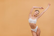© anatoliycherkas - Beautiful Asian Woman Stretching Body Wearing White Underwear on Beige Background