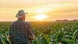 © Adriana - Senior farmer standing in field looking at his crop at sunset.
