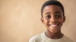 © 娜 赵 - A young African American boy stands against a soft background, smiling at the camera with confidence.