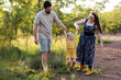 © Austockphoto - Happy young Australian family parents swinging toddler kid together in countryside