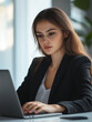 © Daryl - Confident young woman working on a laptop. Professional businesswoman in a suit, focused on work, representing entrepreneurship, online business, and corporate success. Perfect for career design