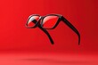 © MrHamster - Black rimmed glasses are levitating on a red vibrant backdrop