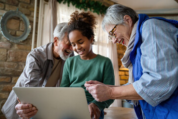 Wall Mural - Mature couple with grandchild look at laptop screen and learn how to make video call or use laptop