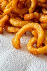 Wall Mural - Seasoned spicy curly fries, freshly fried, on kitchen paper towel absorbing the grease. Fast food background backdrop.