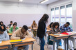 © Koldo_Studio - High school students taking exam with teacher supervising
