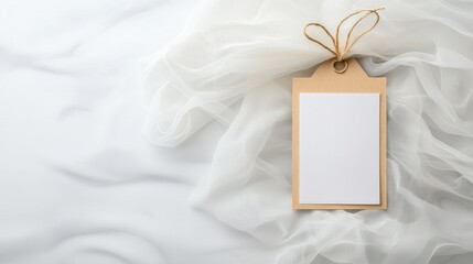 Elegant blank paper card with ribbon on soft, white fabric background for message or invitation.