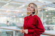 © Westend61 - Portrait of a happy young businesswoman standing at a railing