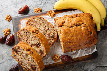 Wall Mural - Gluten free and lactose free Date banana walnuts bread loaf close up on wooden board on table. Horizontal top view from above