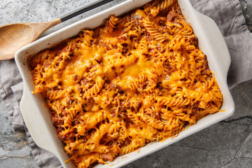 Wall Mural - Homemade Sloppy Joe Casserole with ground beef, pasta and gooey cheddar cheese and baked to perfection in the oven closeup in the baking dish on the table. Horizontal top view from above