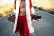 © Westend61 - Mid section of Santa Claus holding a longboard on country road