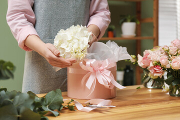 Wall Mural - Florist making beautiful bouquet at table in flower shop, closeup