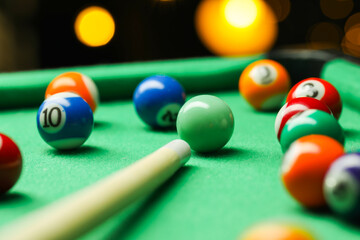 Wall Mural - Many colorful billiard balls and cue on green table indoors, closeup