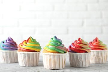 Wall Mural - Delicious cupcakes with colorful cream on grey textured table near white wall, closeup. Space for text