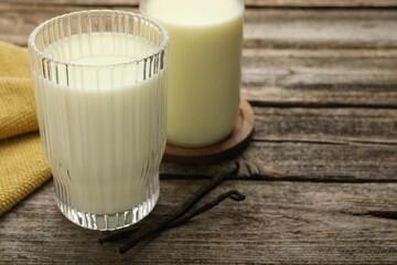 Wall Mural - Delicious vanilla milk and pods on wooden table, closeup. Space for text