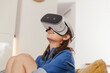 © Westend61 - Young woman using VR glasses at home