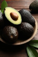 Wall Mural - Fresh ripe avocados and leaves on wooden table, closeup